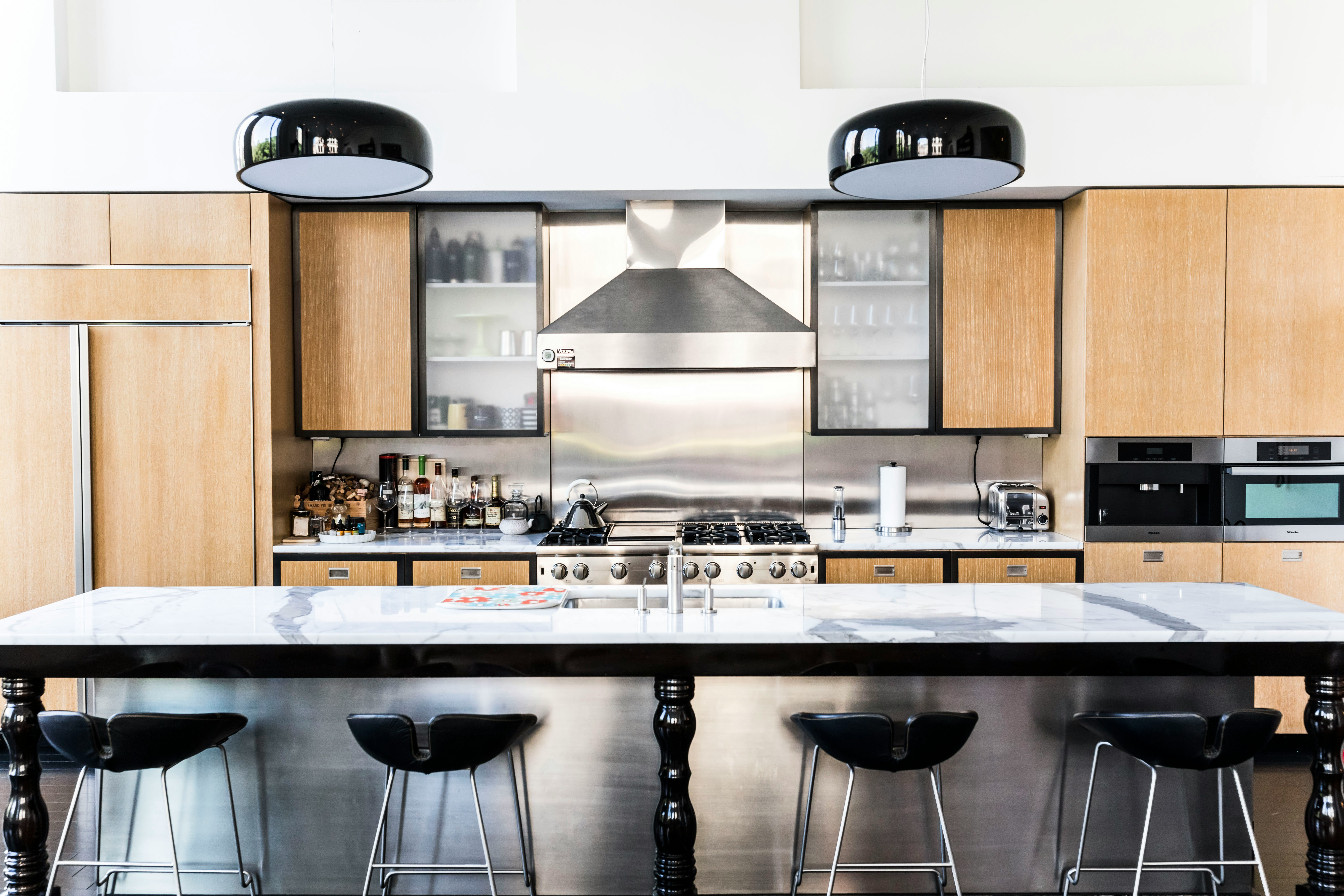 Modern kitchen with stainless steel worktop, range hood, backsplash, and appliance panels